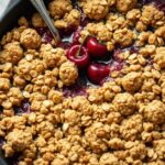 Fresh cherry crumble baked in a cast iron skillet with golden oat topping